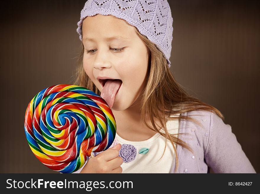 Cute young girl with lollipop and knit cap