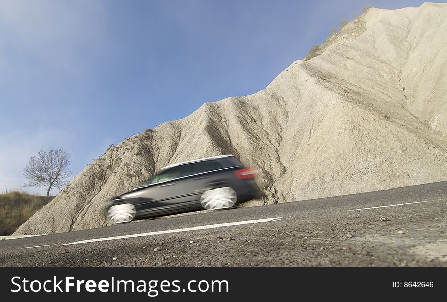 Black car moving in a arid landscape; Spain