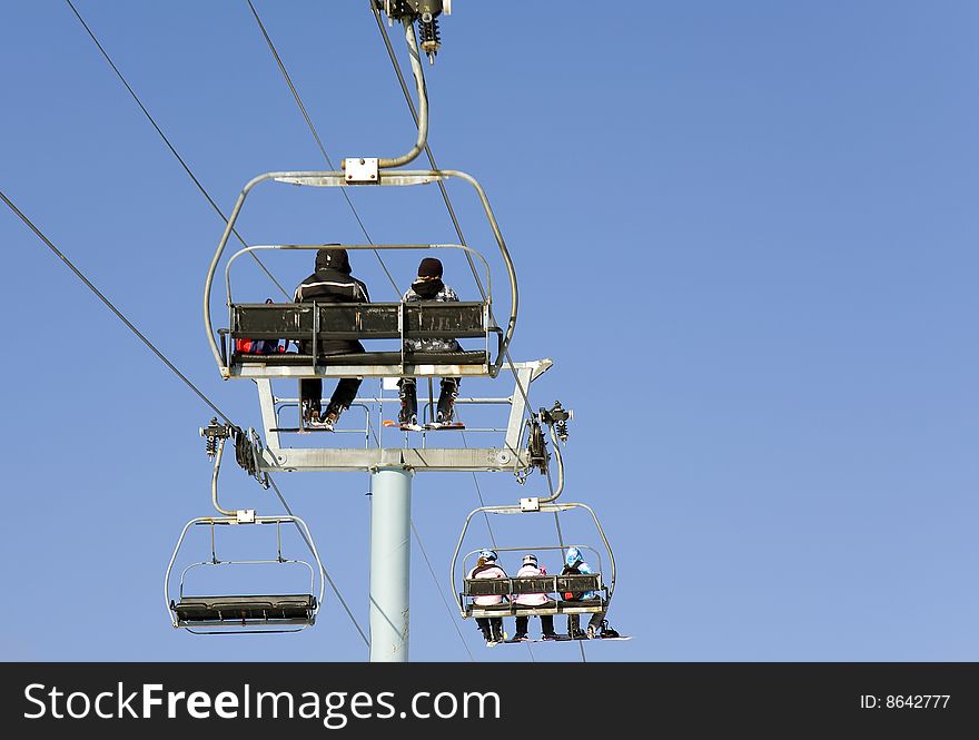 People going to ski in a chair lift. People going to ski in a chair lift.