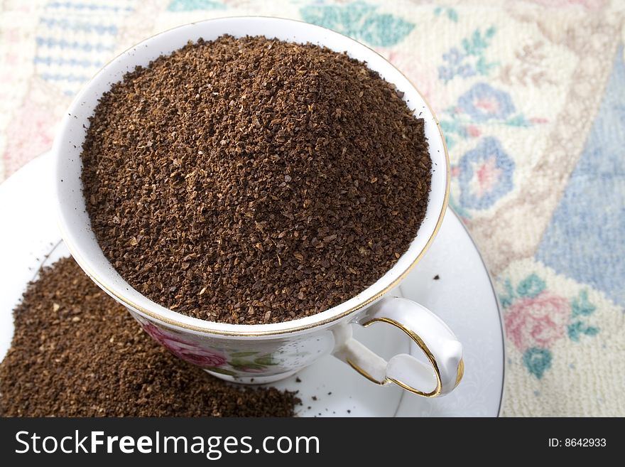 Raw ground coffee overflows a cup