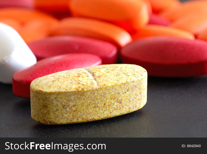 A close-up image of a brown pill with many pills behind it. A close-up image of a brown pill with many pills behind it.