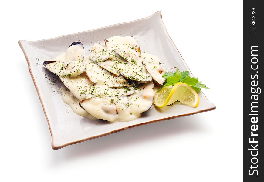 Mussel in white sauce with lemon slice and parsley strewed with dill on the squared plate over white background