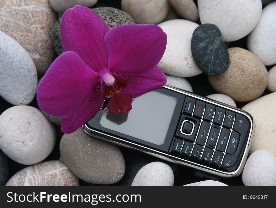 Mobile phone on stone background with a orchid