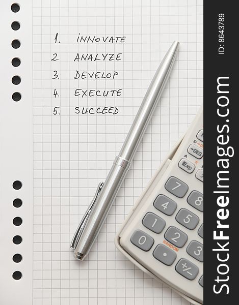 Elegant silver pen and scientific calculator on white spiral notebook (important business steps written on page)