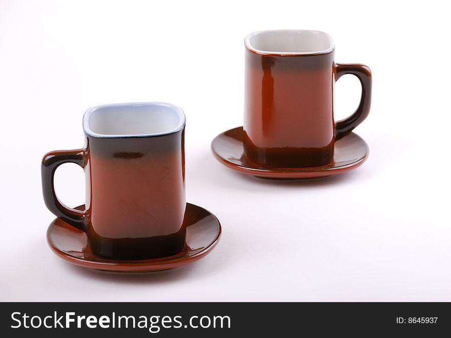 Brown cups for tea and coffee. A small white teapot. Brown cups for tea and coffee. A small white teapot.