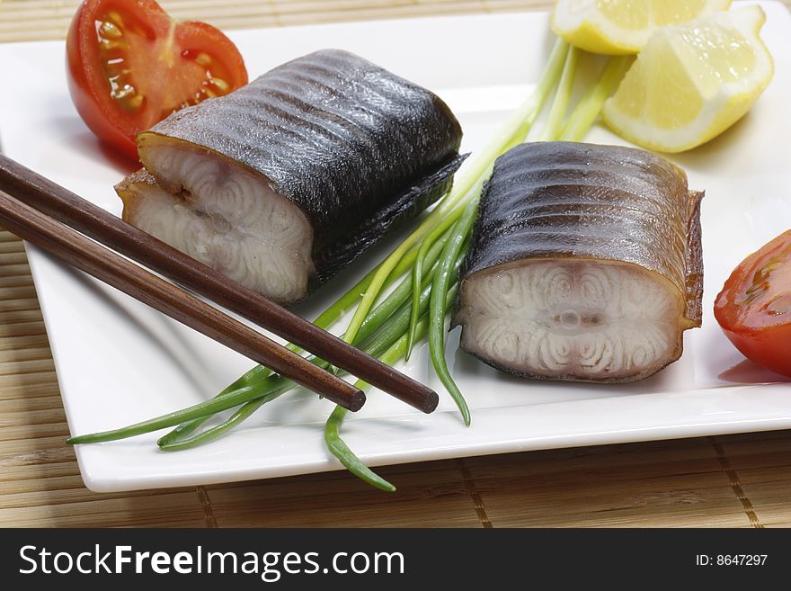 Pieces of smoked eel on a plate with garnish. Pieces of smoked eel on a plate with garnish