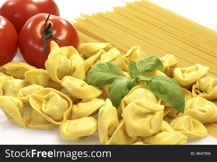 Raw spaghetti and tortellini with basil and tomatoes. Raw spaghetti and tortellini with basil and tomatoes