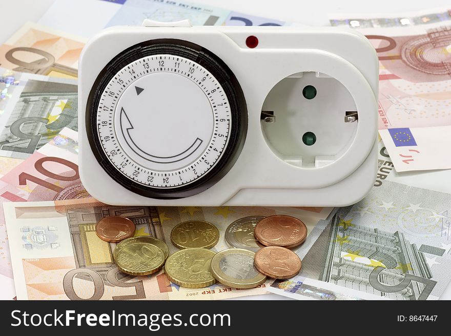 24 hours mechanical timer with Euro coins and bills over white background