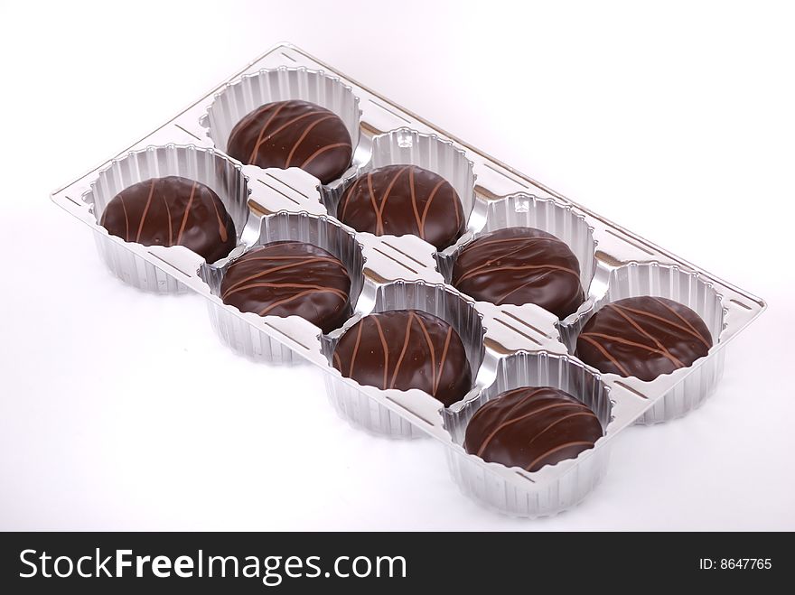 Small chocolate cakes covered with a layer of black chocolate and decorated with a pattern from a milk chocolate.