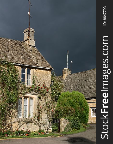 Cotswold house in sunshine with stormclouds approaching