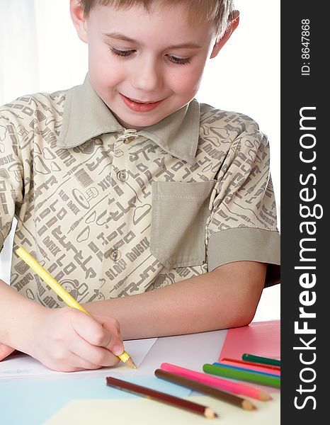 6 year old boy draws pencils sitting for a table. 6 year old boy draws pencils sitting for a table