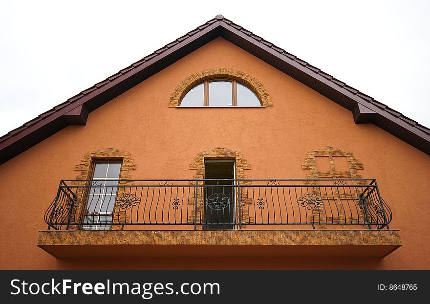 A house detail, red or orange wall and balcony. Old style architecture newly built.