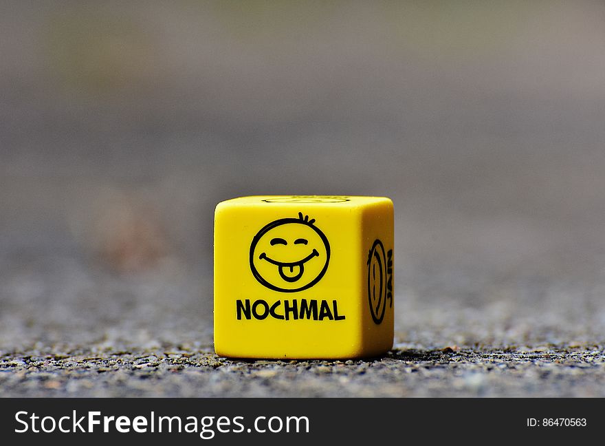 An yellow wooden cube with smiley faces. An yellow wooden cube with smiley faces.