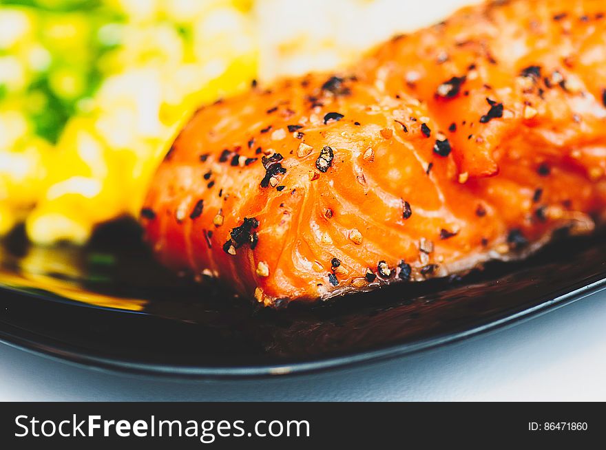 Close up of grilled piece of salmon on black china plate.