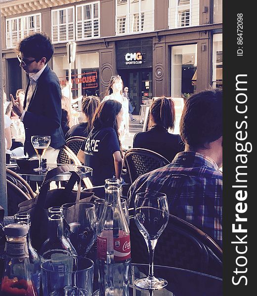 People sitting in an outdoor bar next to a pedestrian street. People sitting in an outdoor bar next to a pedestrian street.