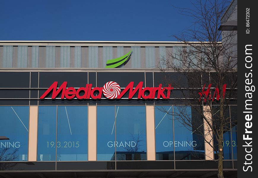 Media Markt logo and sign outside store with grand opening banner on sunny day. Media Markt logo and sign outside store with grand opening banner on sunny day.