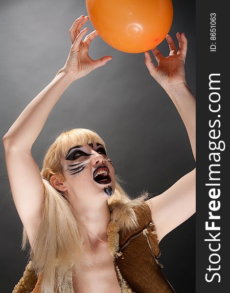 Beatiful young girl with make-up in cat style playing with orange ball. Beatiful young girl with make-up in cat style playing with orange ball.