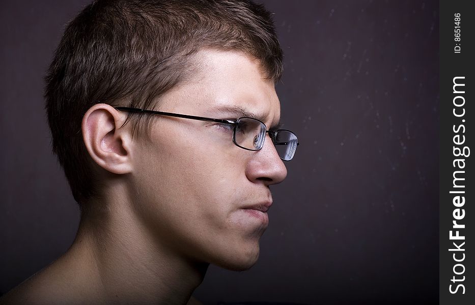 Man in glasses against a dark background.