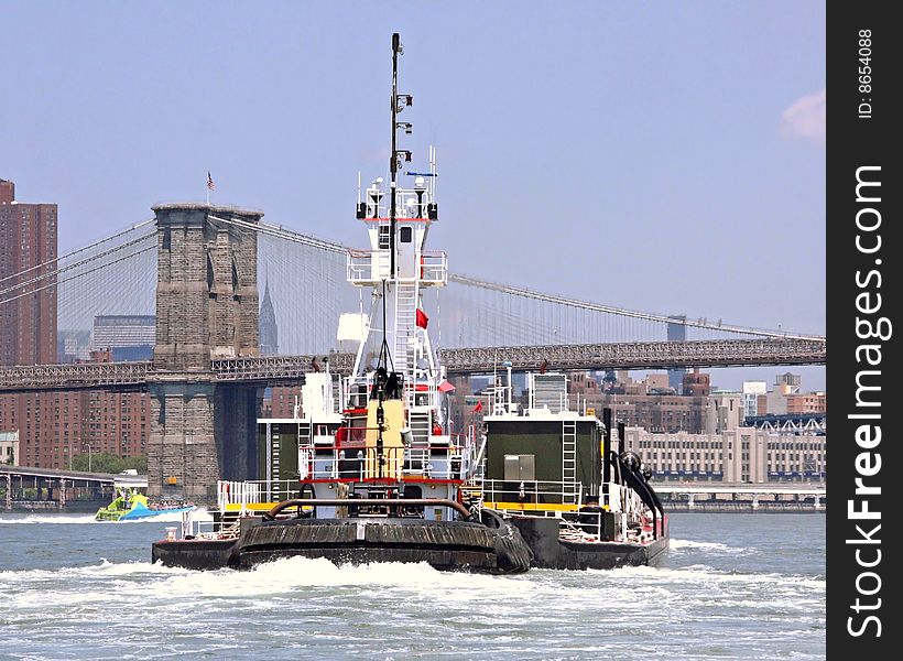 Tugboat going up the East River toward the Brooklyn Bridge with Midtown Manhattan in the background. Tugboat going up the East River toward the Brooklyn Bridge with Midtown Manhattan in the background.