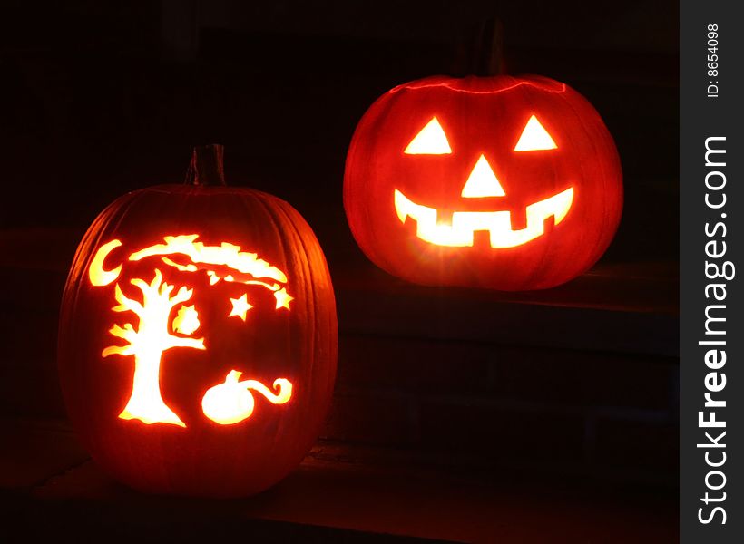 Two pumpkins illuminated from within at night for Halloween.