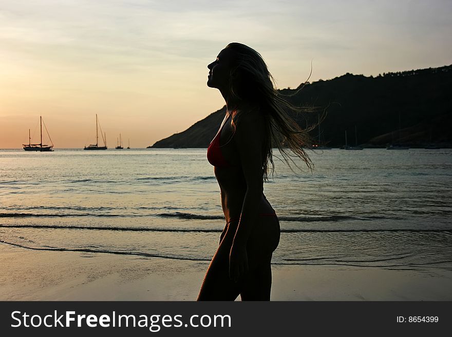 Silhouette of a beautiful young blonde girl on the beach