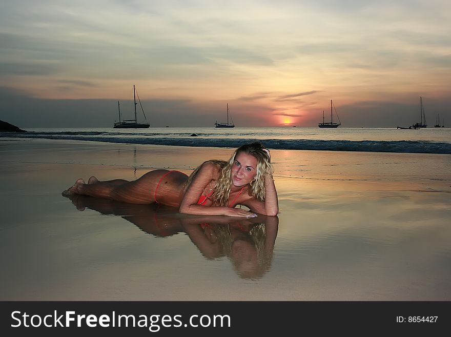 Woman lying on the sand beach at sunset. Woman lying on the sand beach at sunset