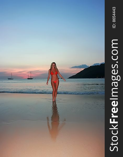 Girl standing on the sunset beach in thailand