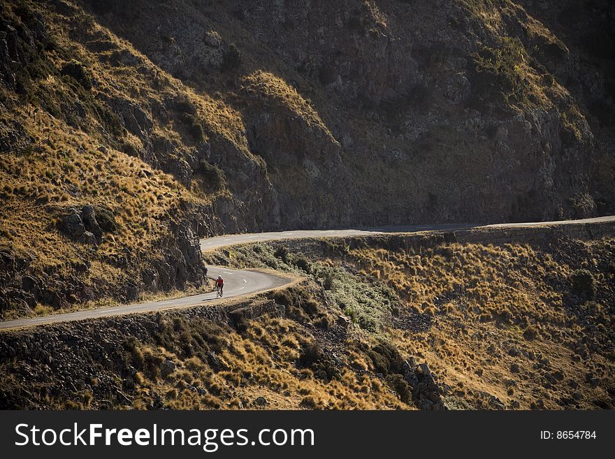 A cyclist on a winding road. A cyclist on a winding road