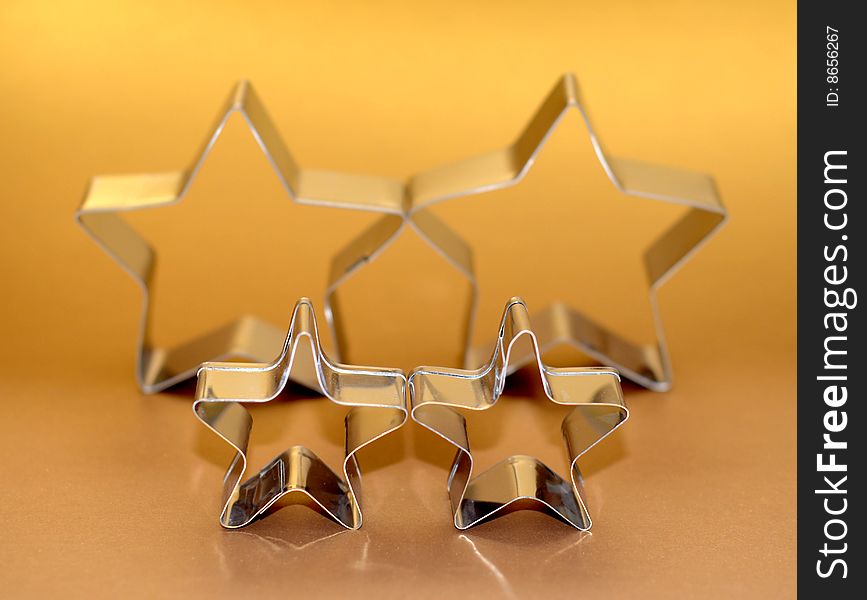 Silver star shaped cookie cutters on gold