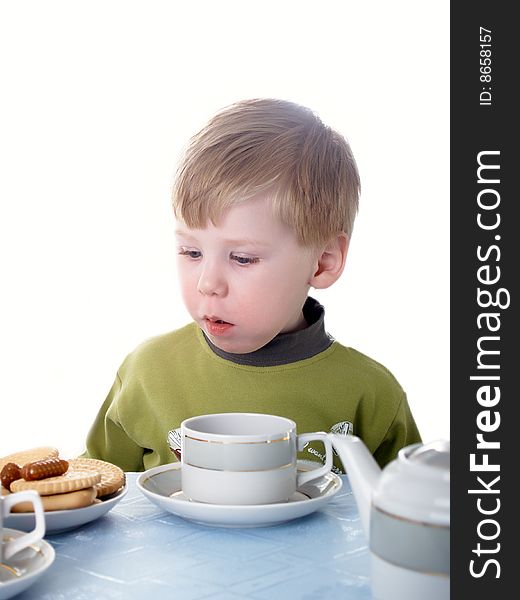 The little boy drinks tea with cookies. The little boy drinks tea with cookies