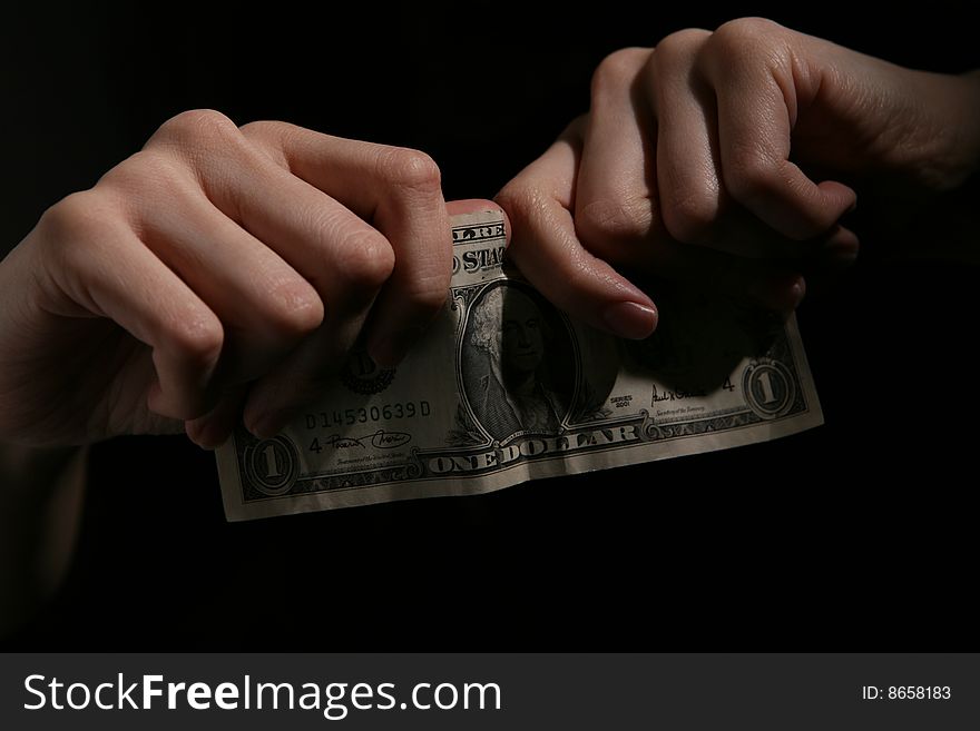 Close-up of human hands tearing dollar banknote.