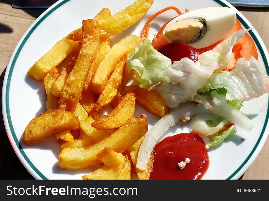 A plate with french-fries, ketchup and salad. A plate with french-fries, ketchup and salad