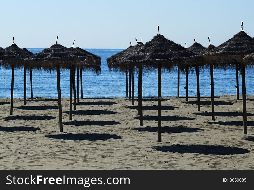 On a beach. sunshades. in the background the sea. On a beach. sunshades. in the background the sea