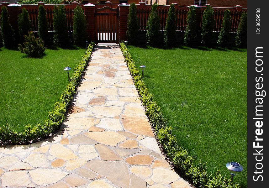 Garden stone path with grass growing up between the stones