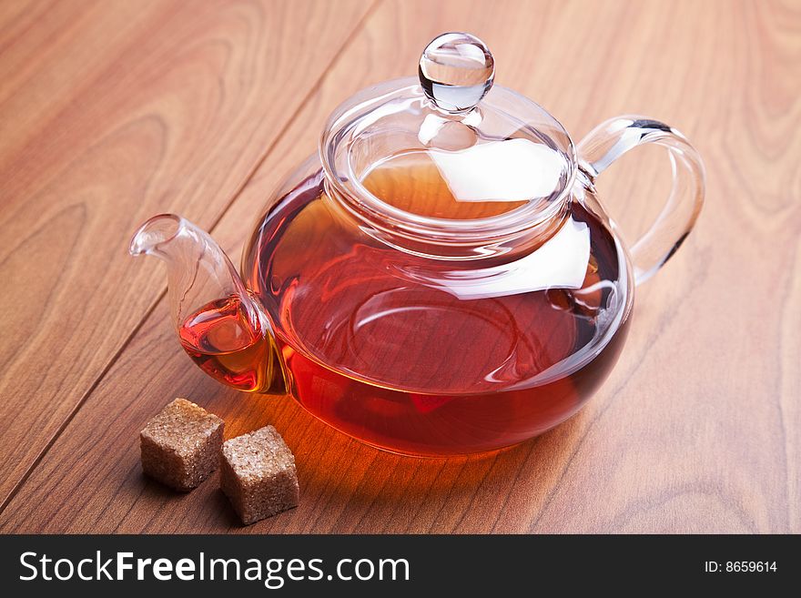 Glass teapot with black tea and sugar