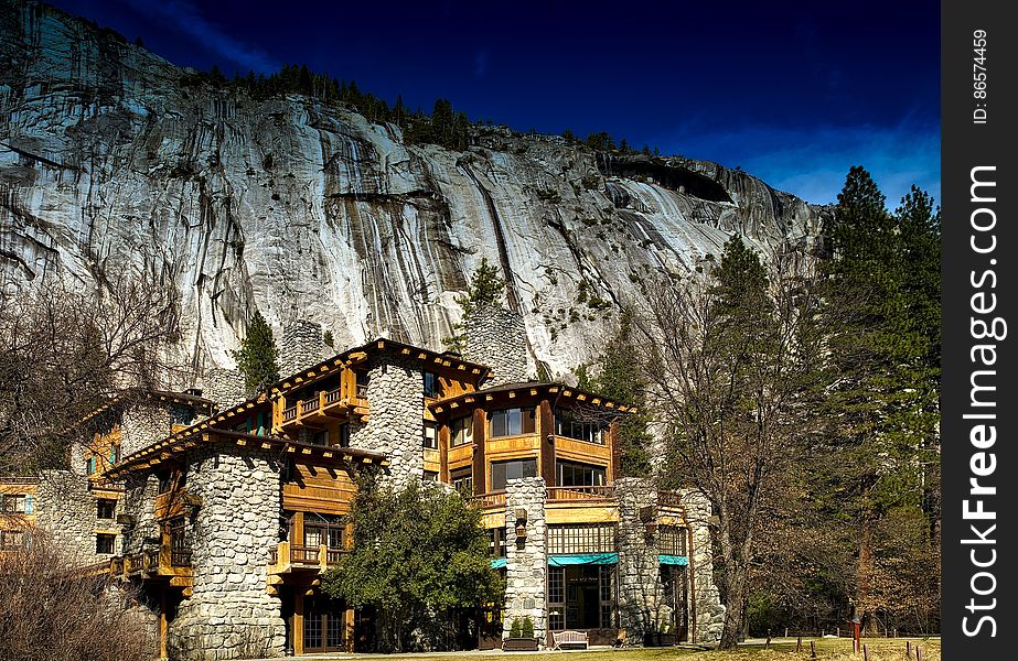 Rustic lodge in Yosemite National Park, California on sunny day against rocky cliff.