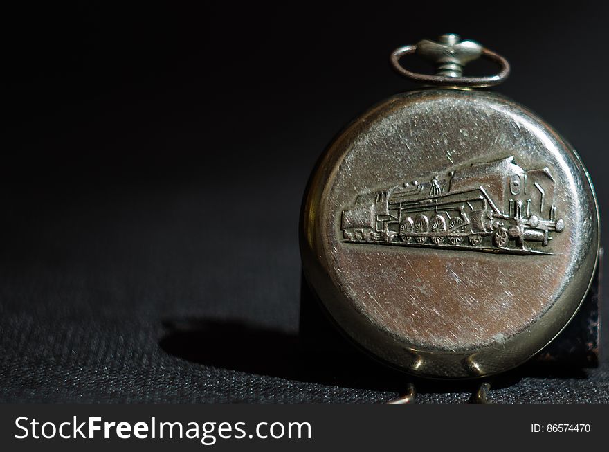 Close up of antique pocket watch with art work of train in metal.