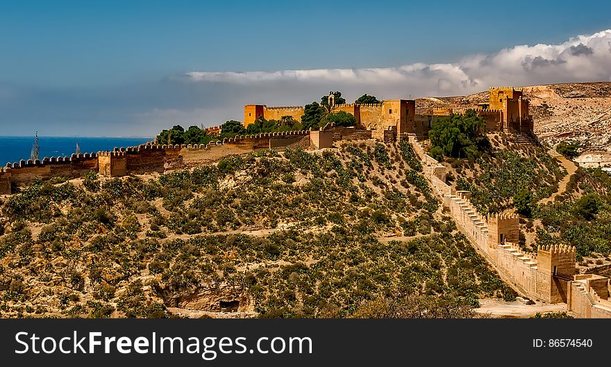 Fortress with stone wall on hillside overlooking waterfront on sunny day. Fortress with stone wall on hillside overlooking waterfront on sunny day.