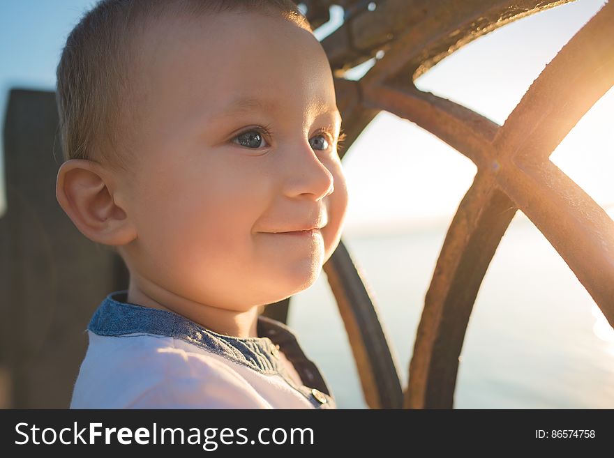 Portrait of smiling child standing next to sunny window.