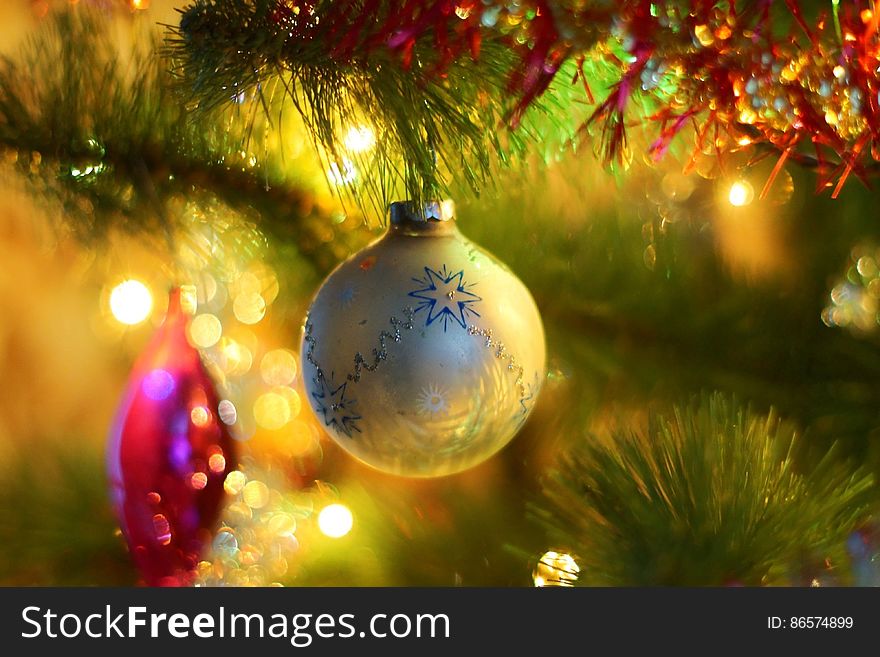 Close up of Christmas ornament on tree with lights.