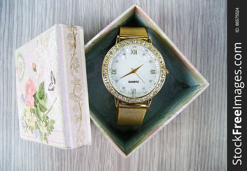 Vintage ornate gold wristwatch inside floral decorative box. Vintage ornate gold wristwatch inside floral decorative box.