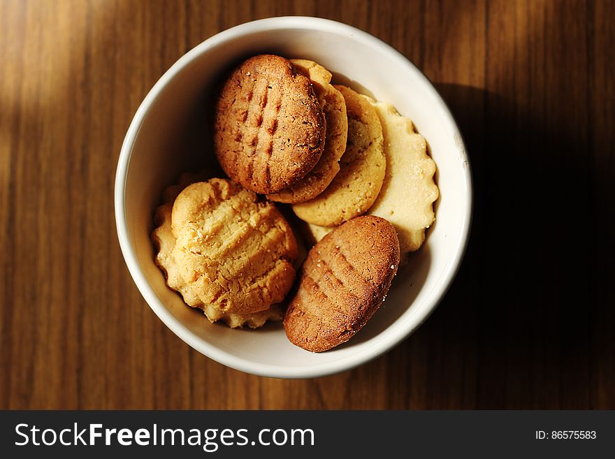 A close up of homemade biscuits in a bowl on a wooden table. A close up of homemade biscuits in a bowl on a wooden table.