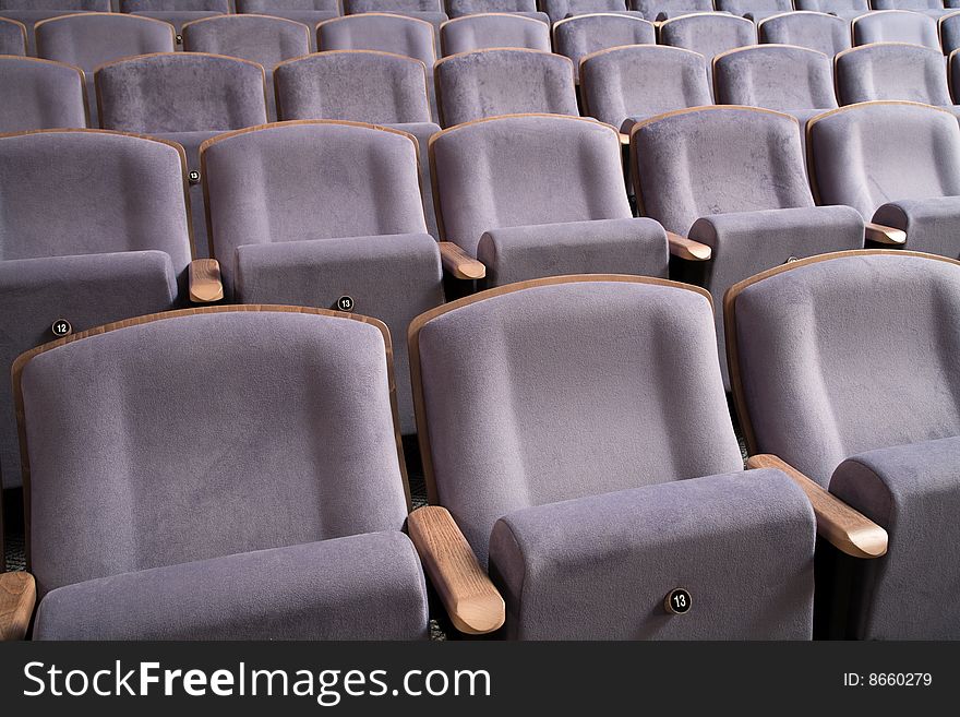 Seats number thirteen. Row of violet blue chairs in auditorium. Seats number thirteen. Row of violet blue chairs in auditorium.