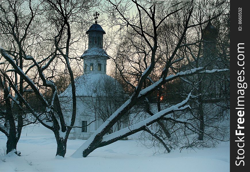Winter trees in the background of the church and the sunset