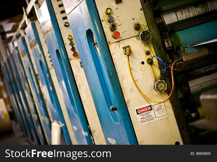 A series of offset printing presses pulling a spool of paper through its rollers. A series of offset printing presses pulling a spool of paper through its rollers.