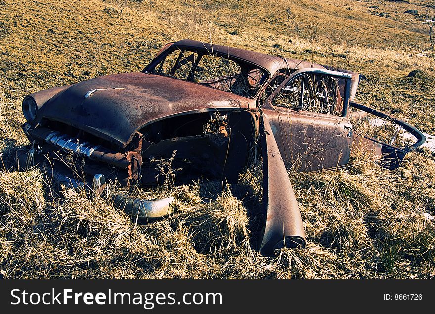 An old rusty abandoned car in a field in Vermont.