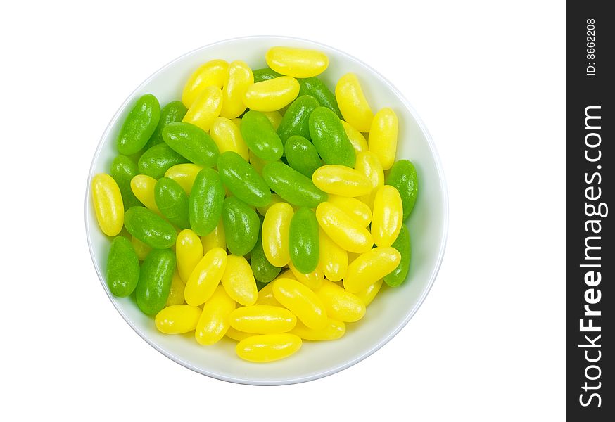 A bowl of green and yellow jelly beans isolated on a white background