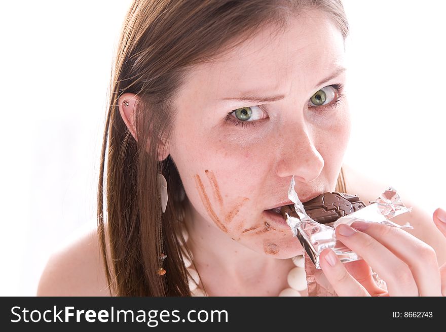 Closeup portrait of serious woman eating a chocolate bar. Isolated over white