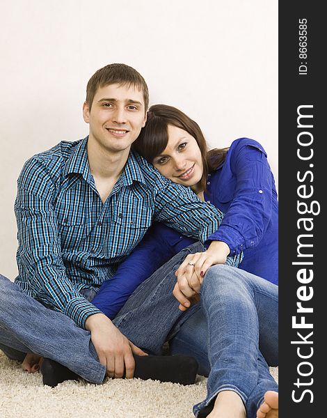 A young couple sitting on the floor in their living room.