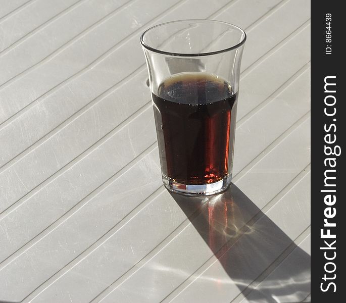 A half glass of coke drink on a white table